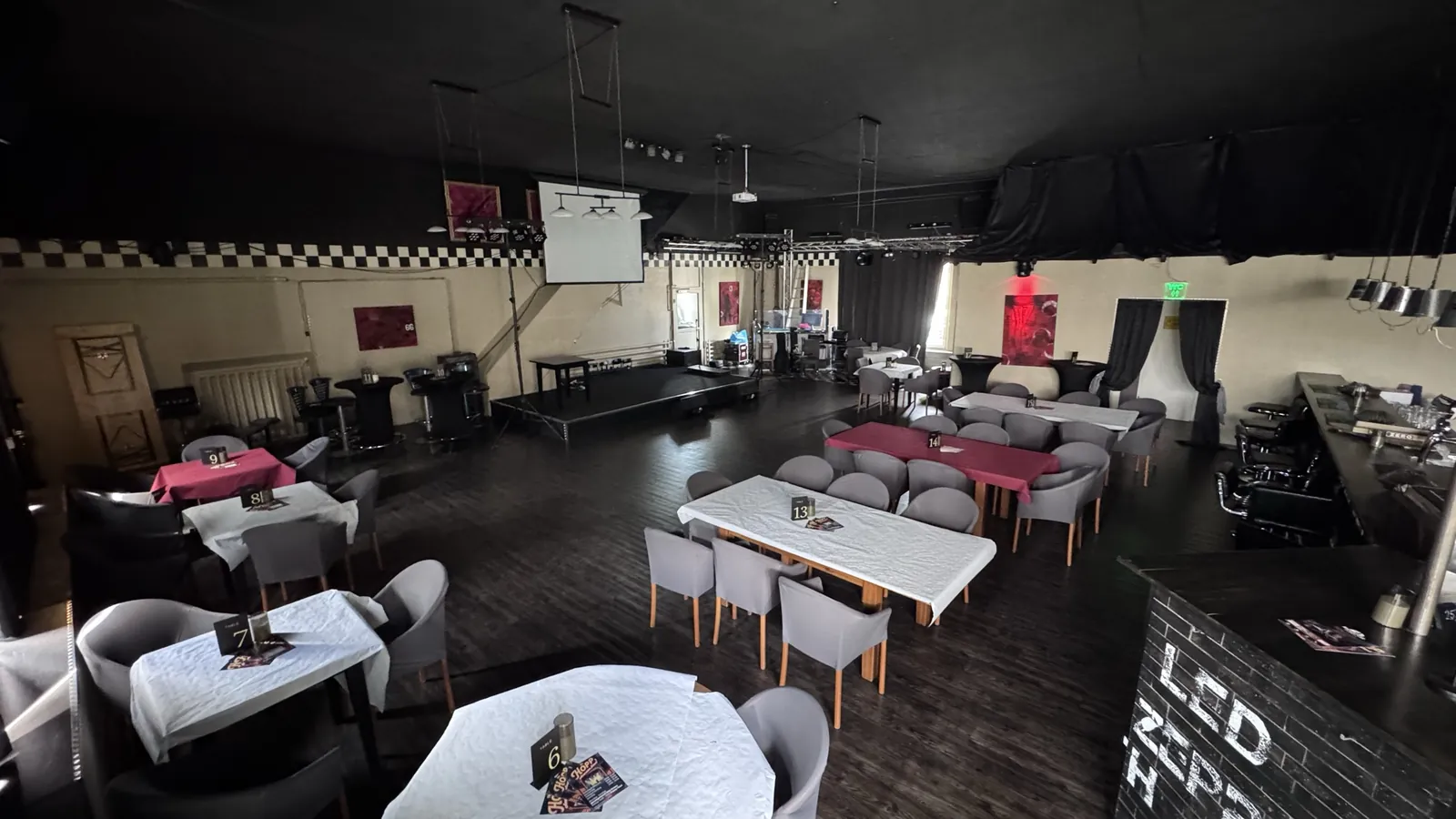 Der Saal mit Bühne, Leinwand, Tischen und Bar